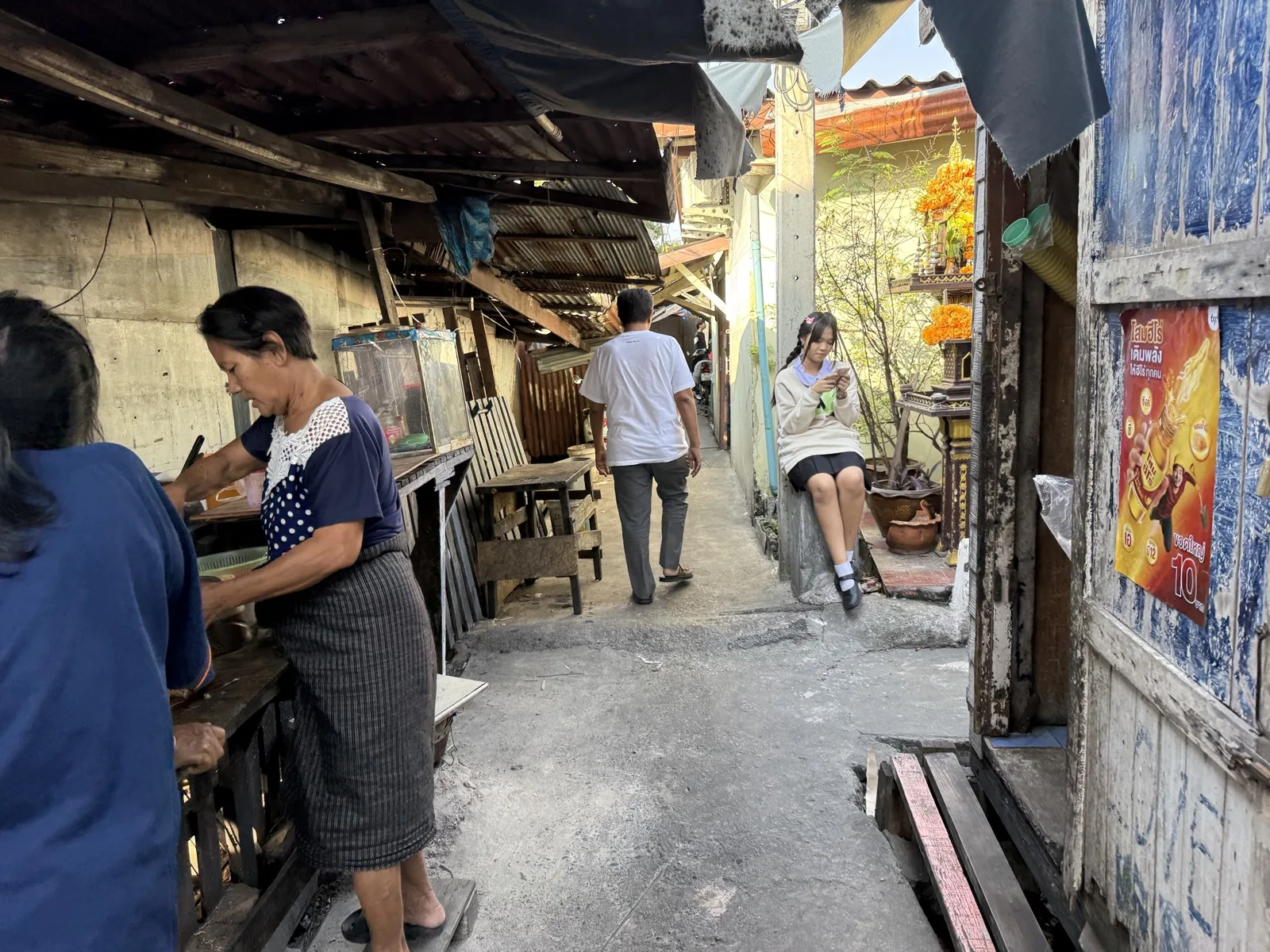 People in a narrow urban walkway in a dense community setting.