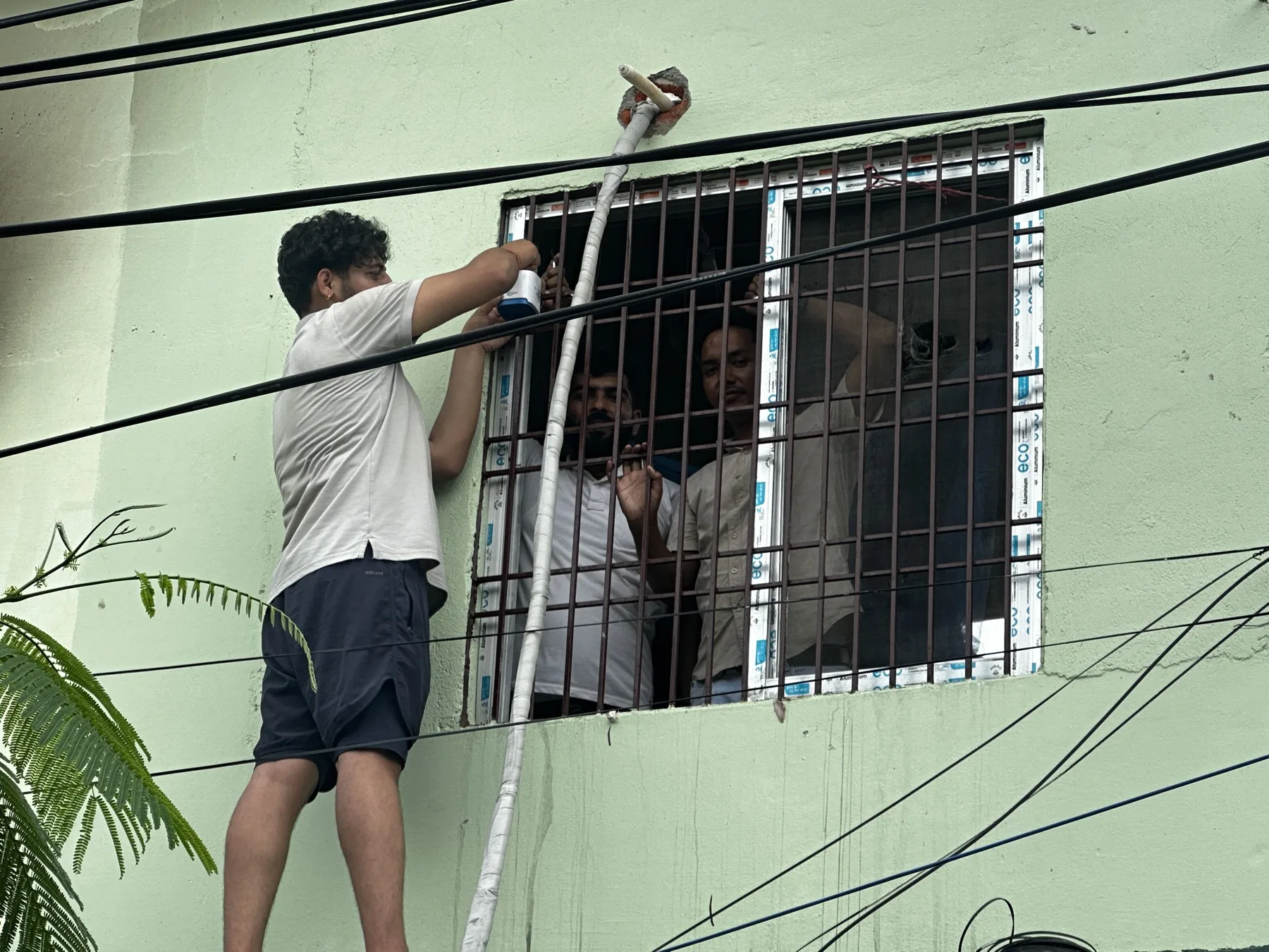 Community members installing an air quality monitor outside a building.